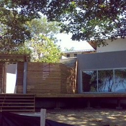 Driveway/front approach to the villa under tall trees in afternoon light (Dos Gueckos)
