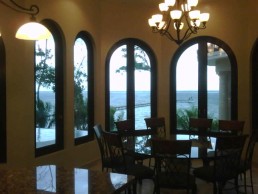 Formal dining room with tall arched windows and chandelier by Hugo Coello