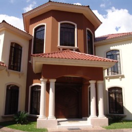 Two-story stucco residence with covered entry and balcony (Casa Flores)
