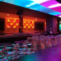 Umami Bar – interior with stage lighting, bar counter, and vibrant color wash