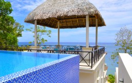 Swimming pool beneath a shaded pavilion with ocean backdrop